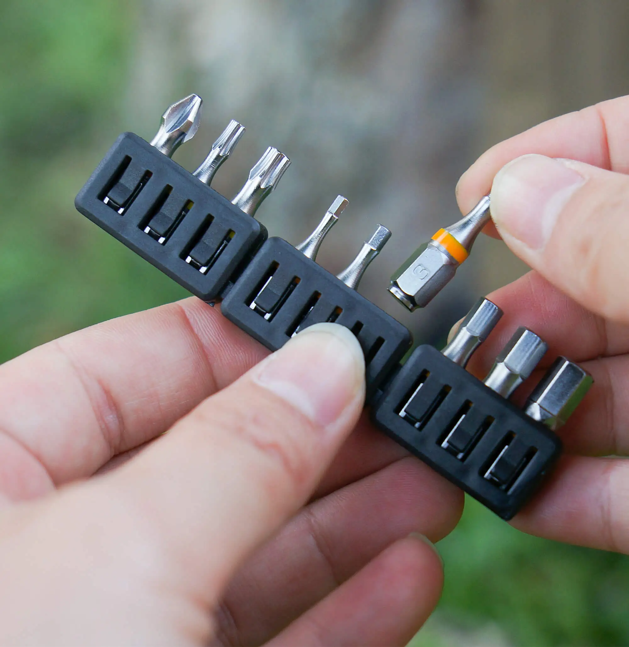 Hand holding the 711L bit tray from the 9pcs color‑coded 1/4” set, filled with laser‑engraved sizes for instant identification and hassle-free selection