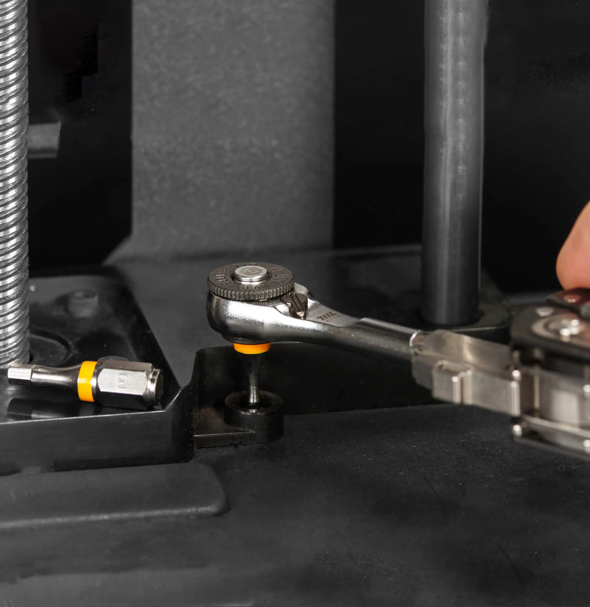 Close-up of a 711L bit from the 9pcs color‑coded 1/4” set inserted into a ratchet on a workbench, demonstrating the premium S2 alloy steel construction for exceptional durability