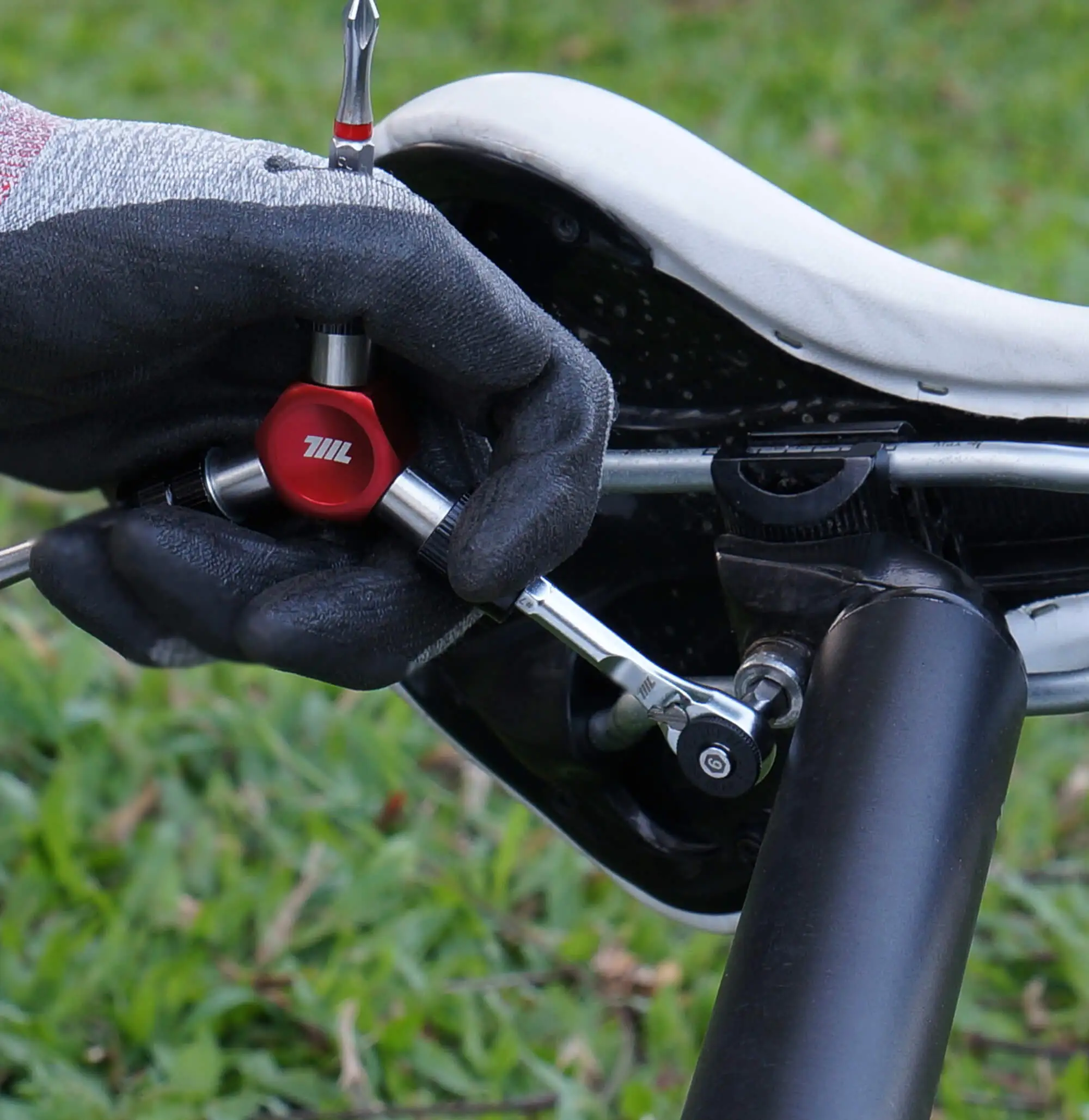 Gloved hand using a 711L hex bit from the 9pcs color‑coded 1/4” bit set on a bicycle seat clamp - part of the complete bit set for DIY and automotive tasks